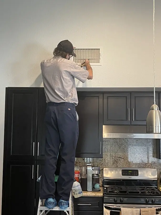 Technician inspecting an air vent during HVAC service in Center